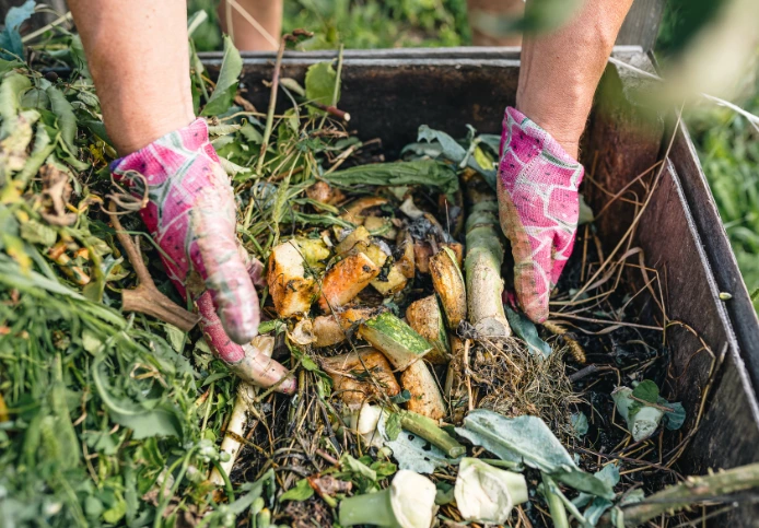 Gloved hands working a home compost pile